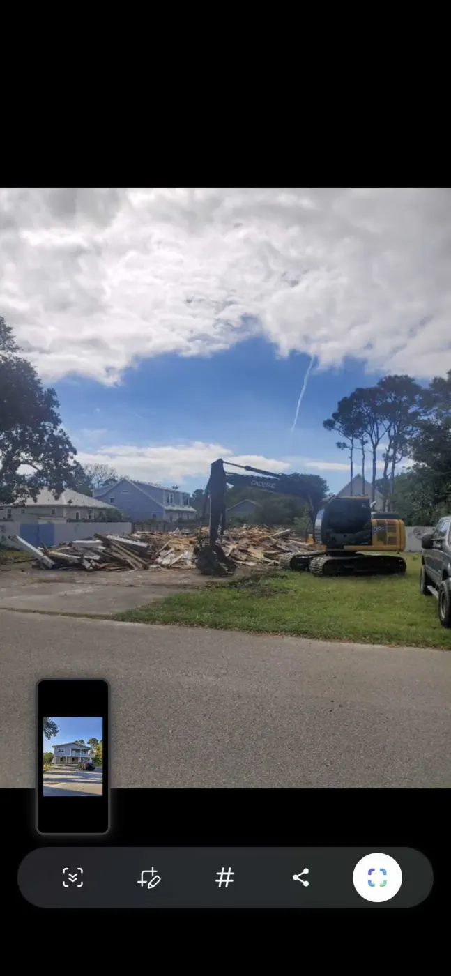 Excavator tearing down an old wood-frame house on a lot near Burgaw, NC