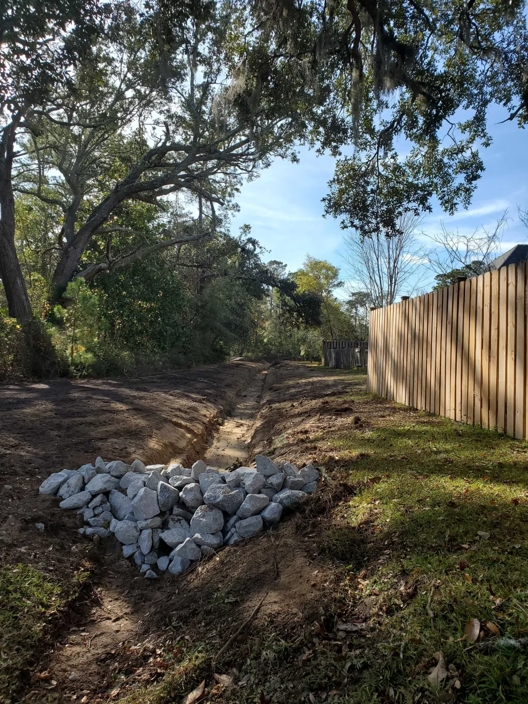 Rock-lined drainage run along a fence line