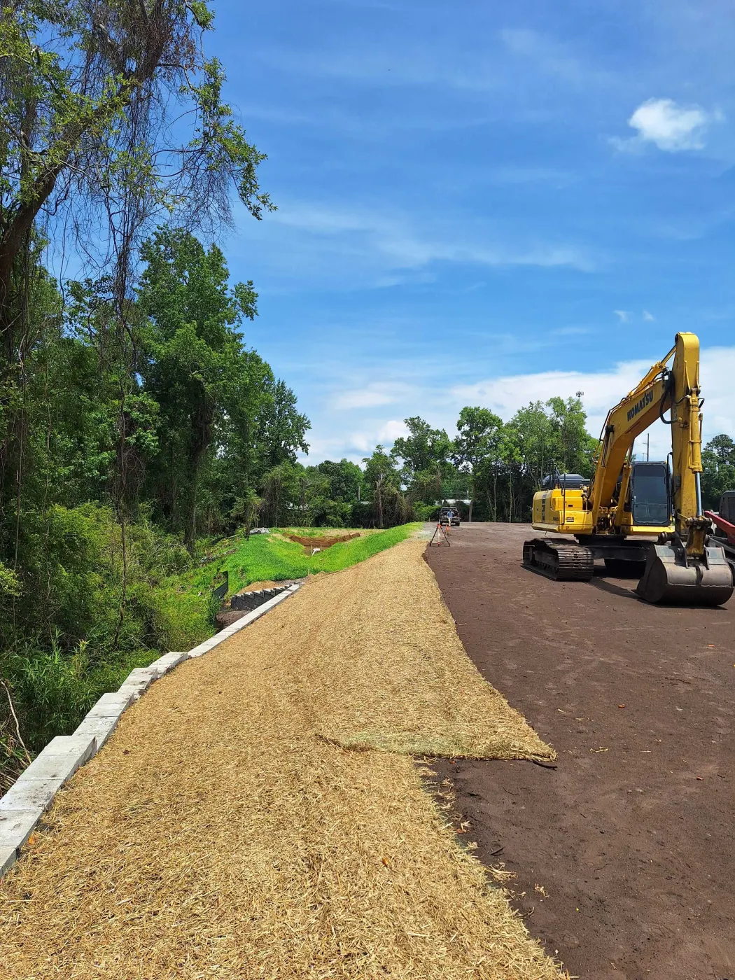 New gravel driveway with straw-lined shoulders through the trees